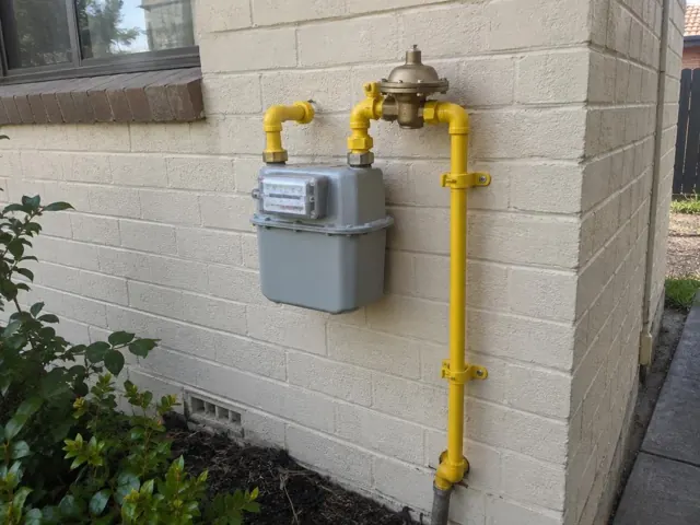 Exterior gas meter and regulator on a cream brick wall beside a window in Lalor Park