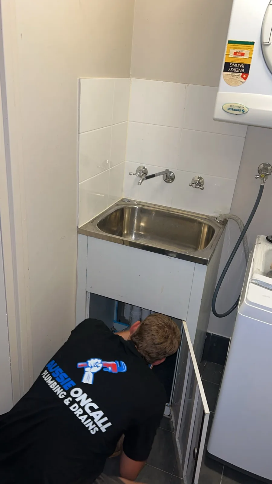 A plumber servicing a laundry sink
