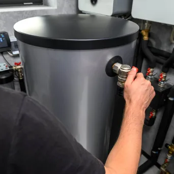 A plumber adjusting the controls on a hot water unit